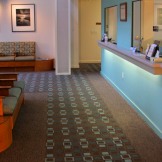 The retro pattern of the carpet gives a hospitality look to the lobby and sets the theme for the color palette. Carpet by Masland